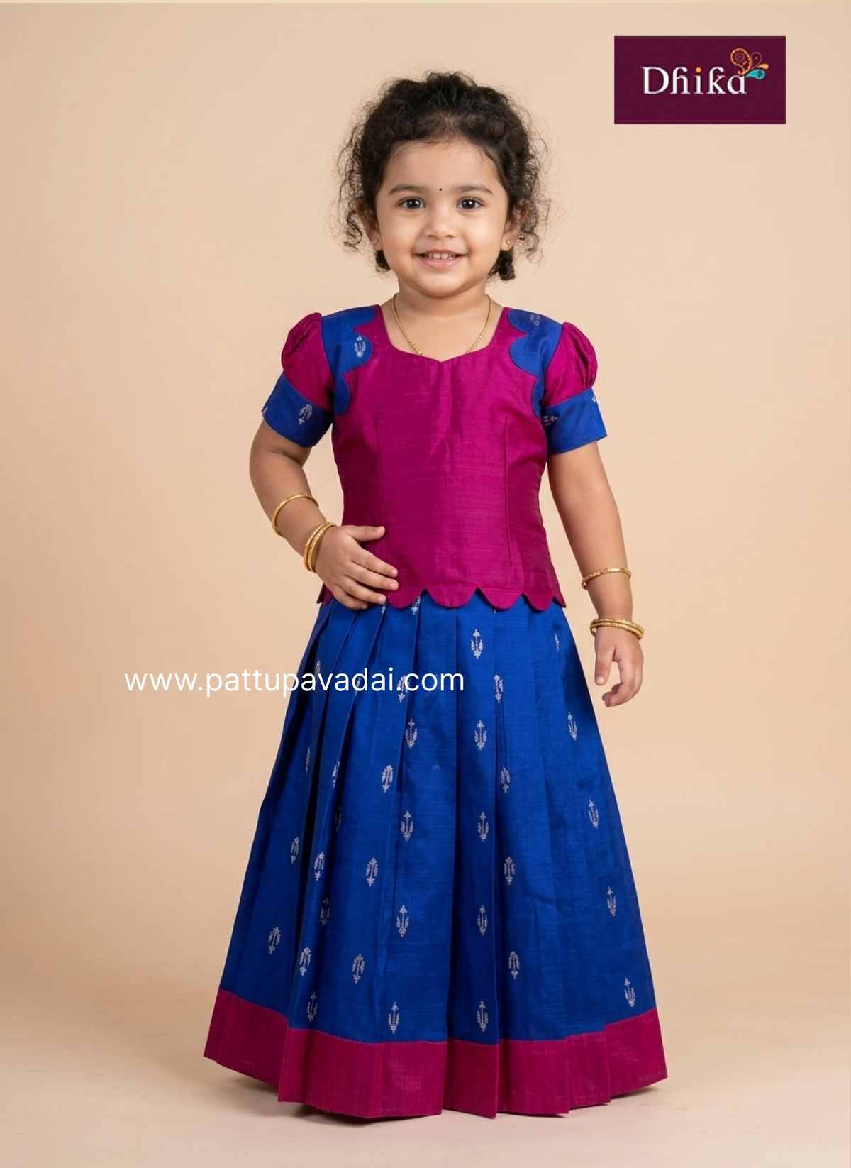 Child wearing a traditional outfit with pink blouse and blue skirt on a beige background, featuring the Drika brand.