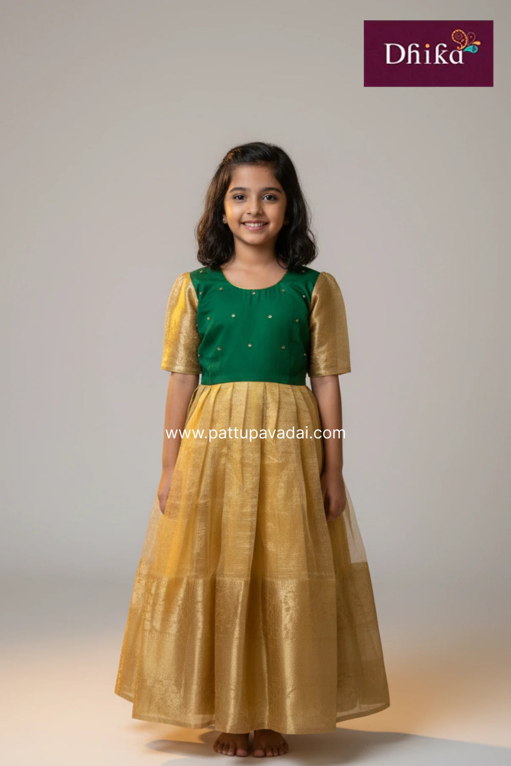 Young girl wearing a green and gold traditional outfit with 'Dhika' branding.