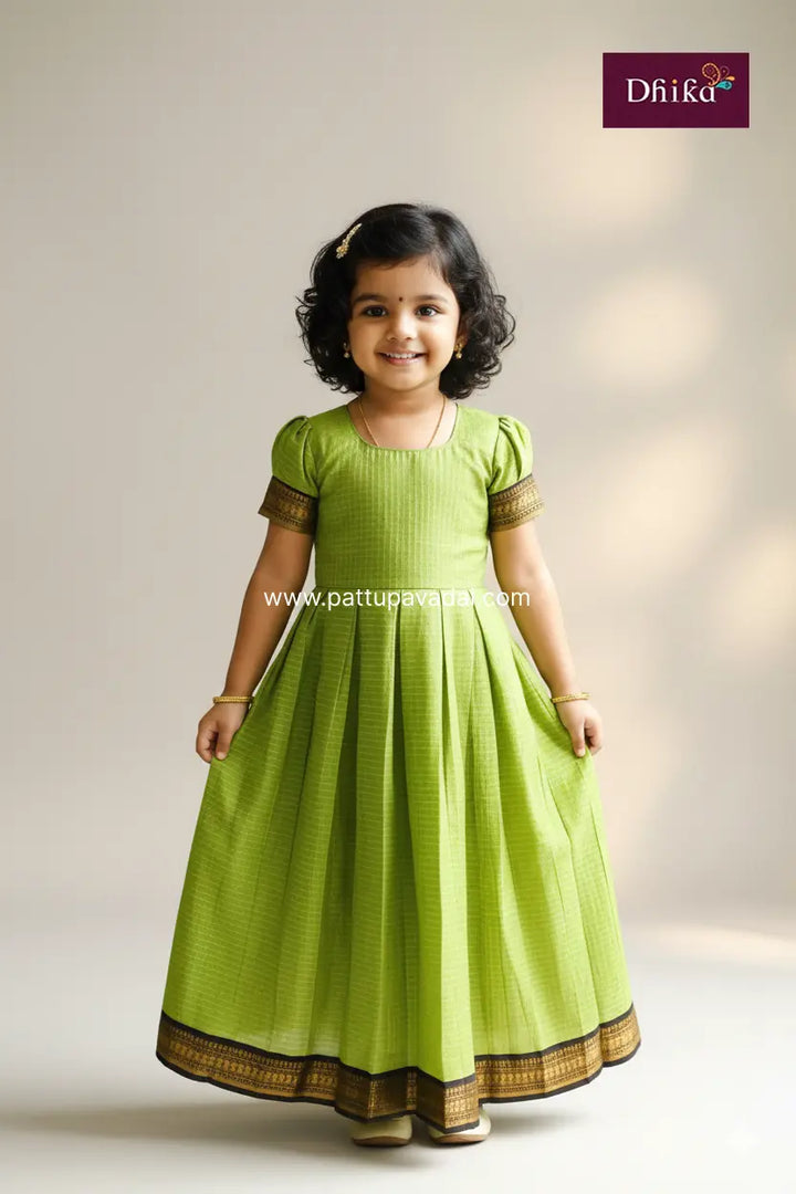 Young girl wearing a green traditional dress with gold accents on a plain background