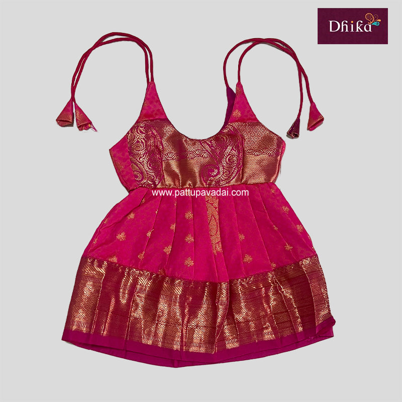 A traditional Indian pink silk frock with golden and red floral patterns and pleated design.