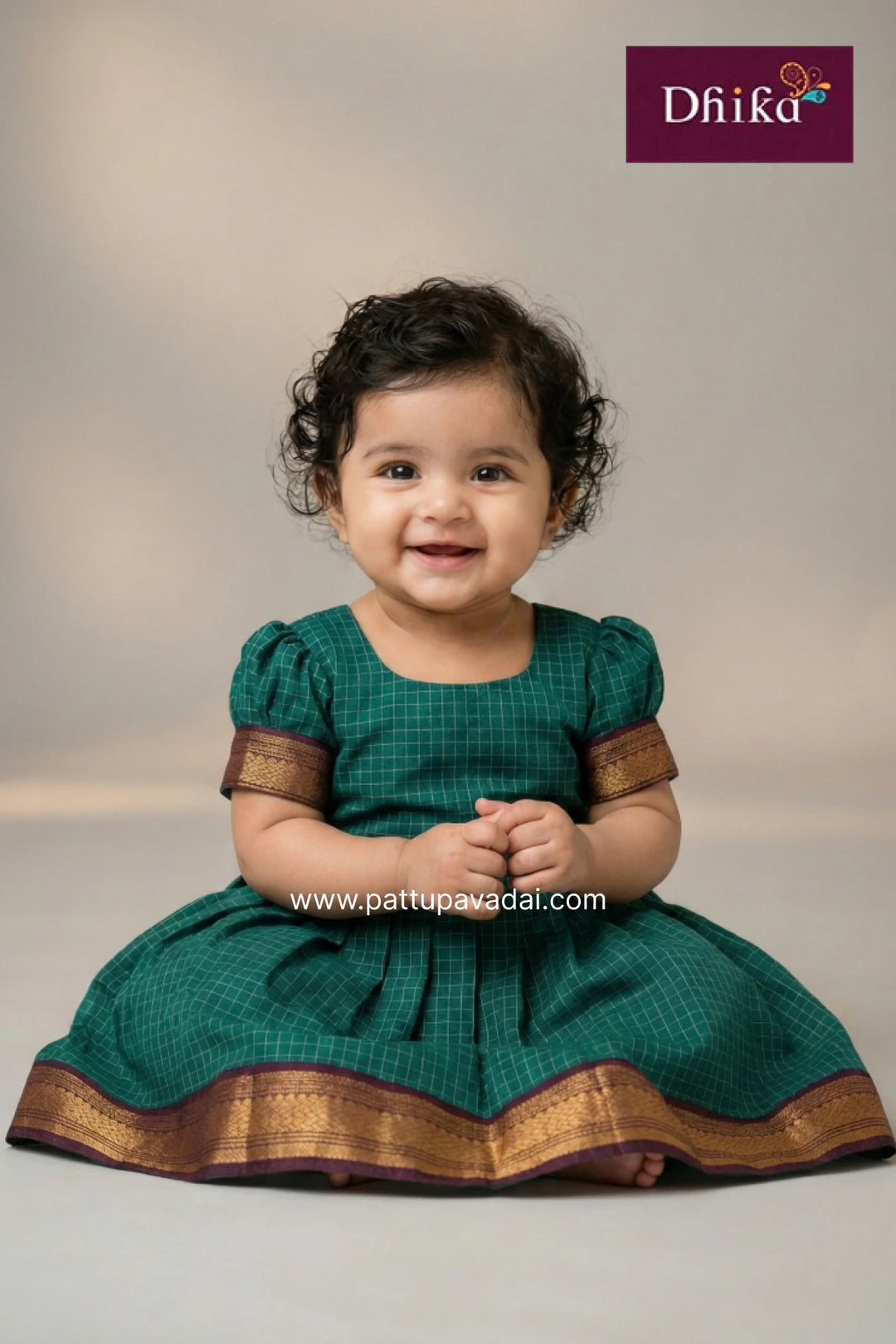 Child wearing a green traditional outfit with gold accents, sitting on a light gray background.