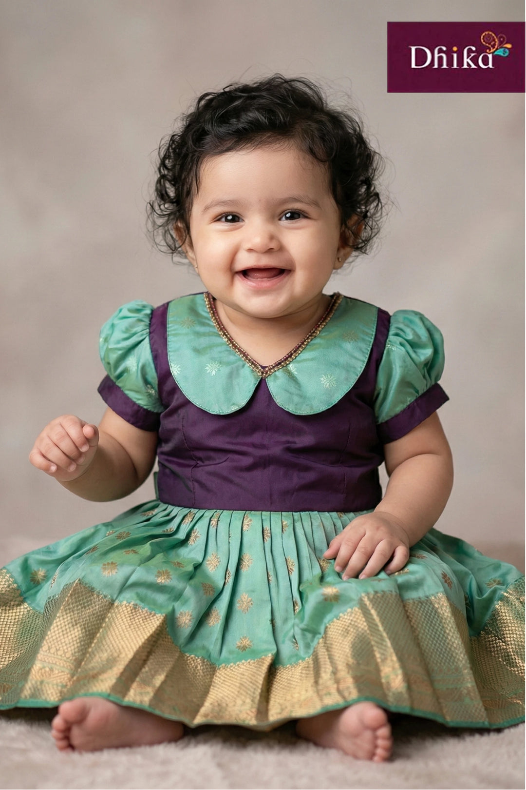 Child wearing a green and purple dress with 'Dhika' branding in the corner.