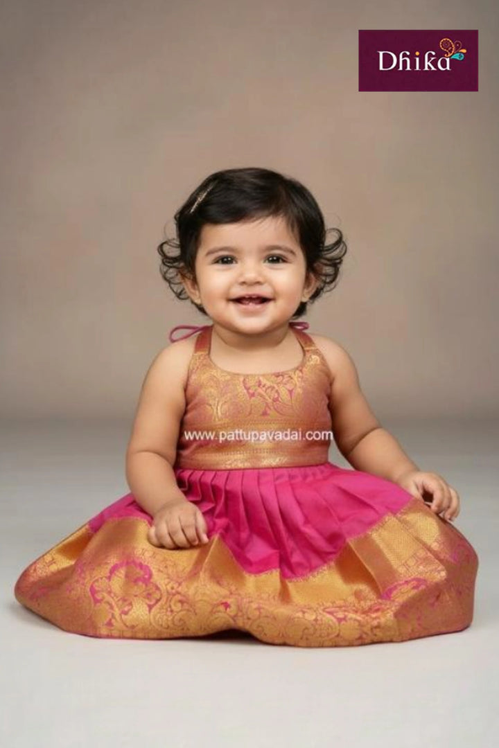 Child wearing a traditional outfit with pink and gold colors on a plain background