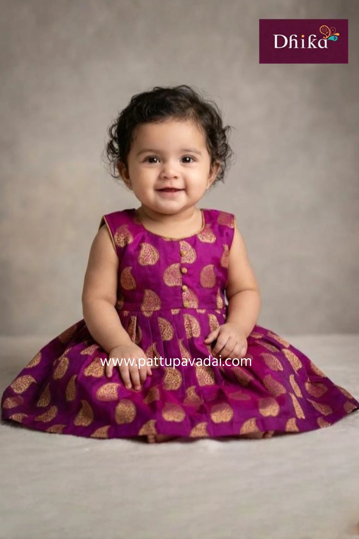 Child wearing a purple dress with gold patterns against a neutral background, featuring the brand 'Dhika'.