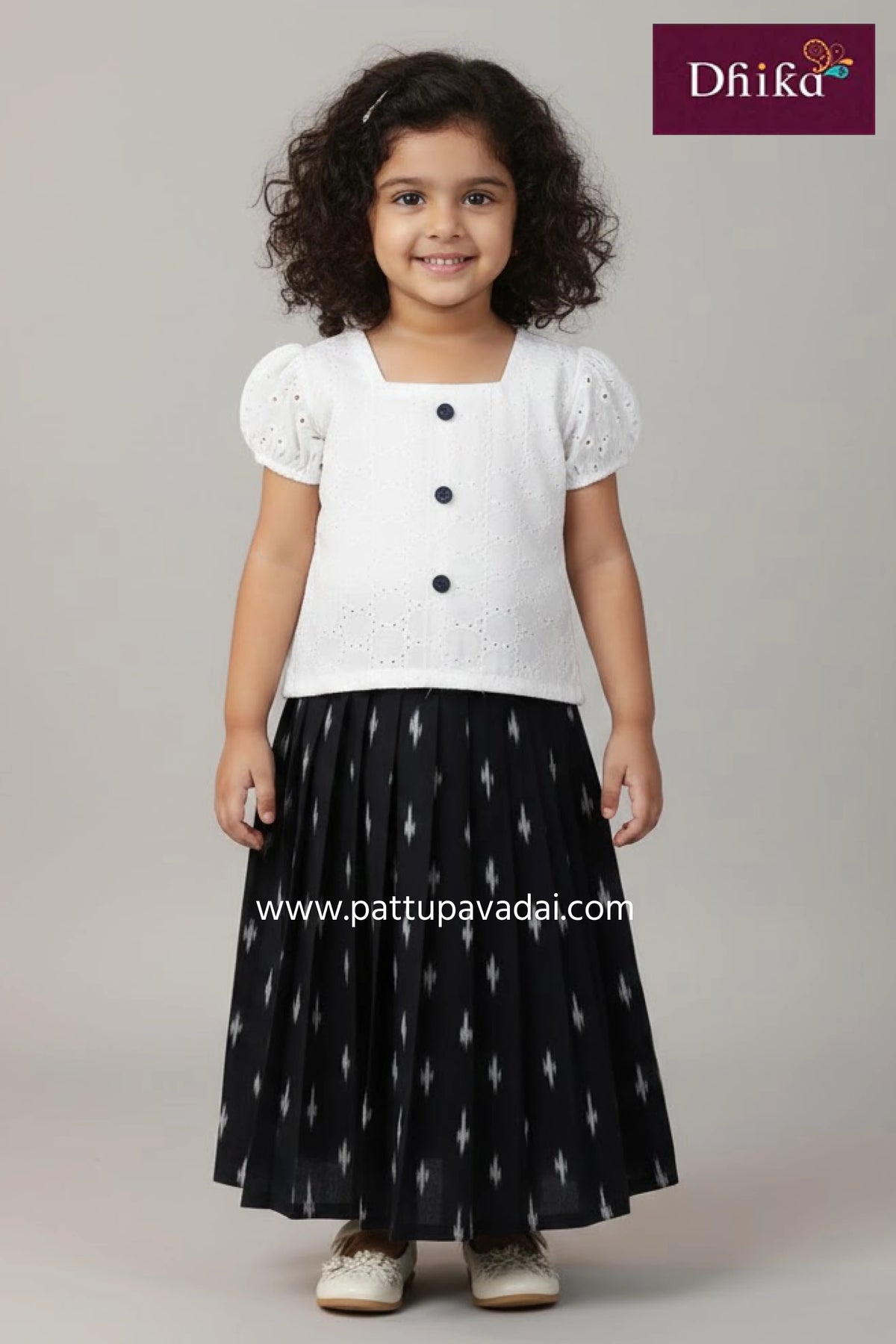 Young girl wearing a pink and navy dress with floral patterns, standing against a plain background.