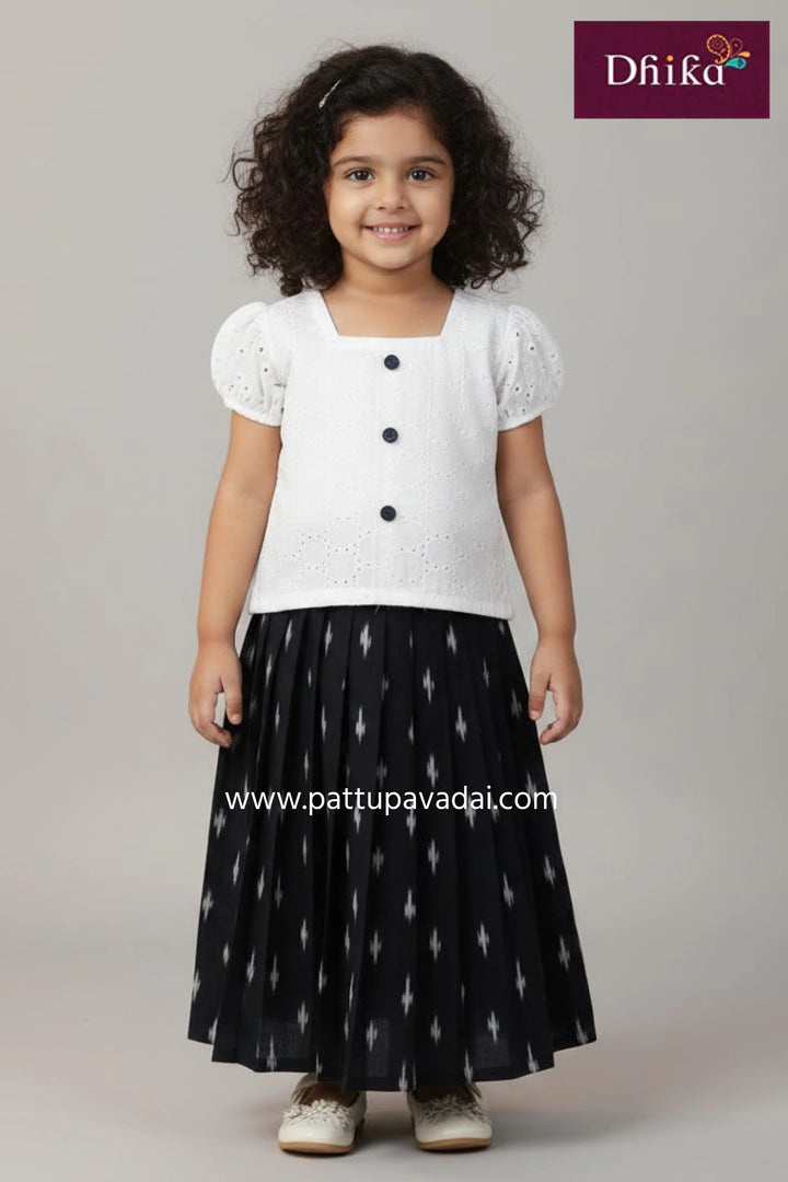 Young girl wearing a pink and navy dress with floral patterns, standing against a plain background.
