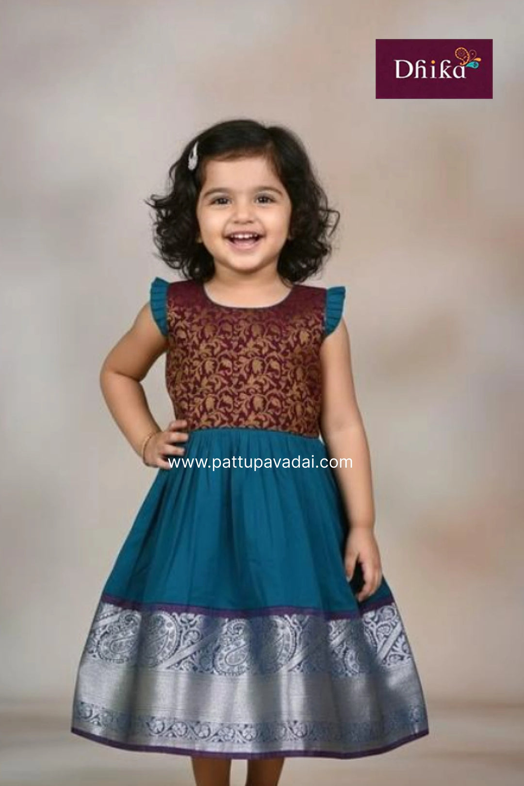 Young girl wearing a traditional dress with floral patterns, brand 'Dhika' visible.