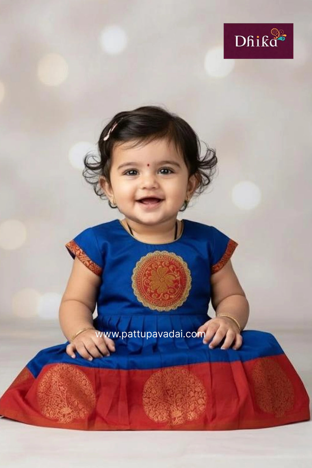 Baby wearing a blue and red traditional outfit with a blurred white background