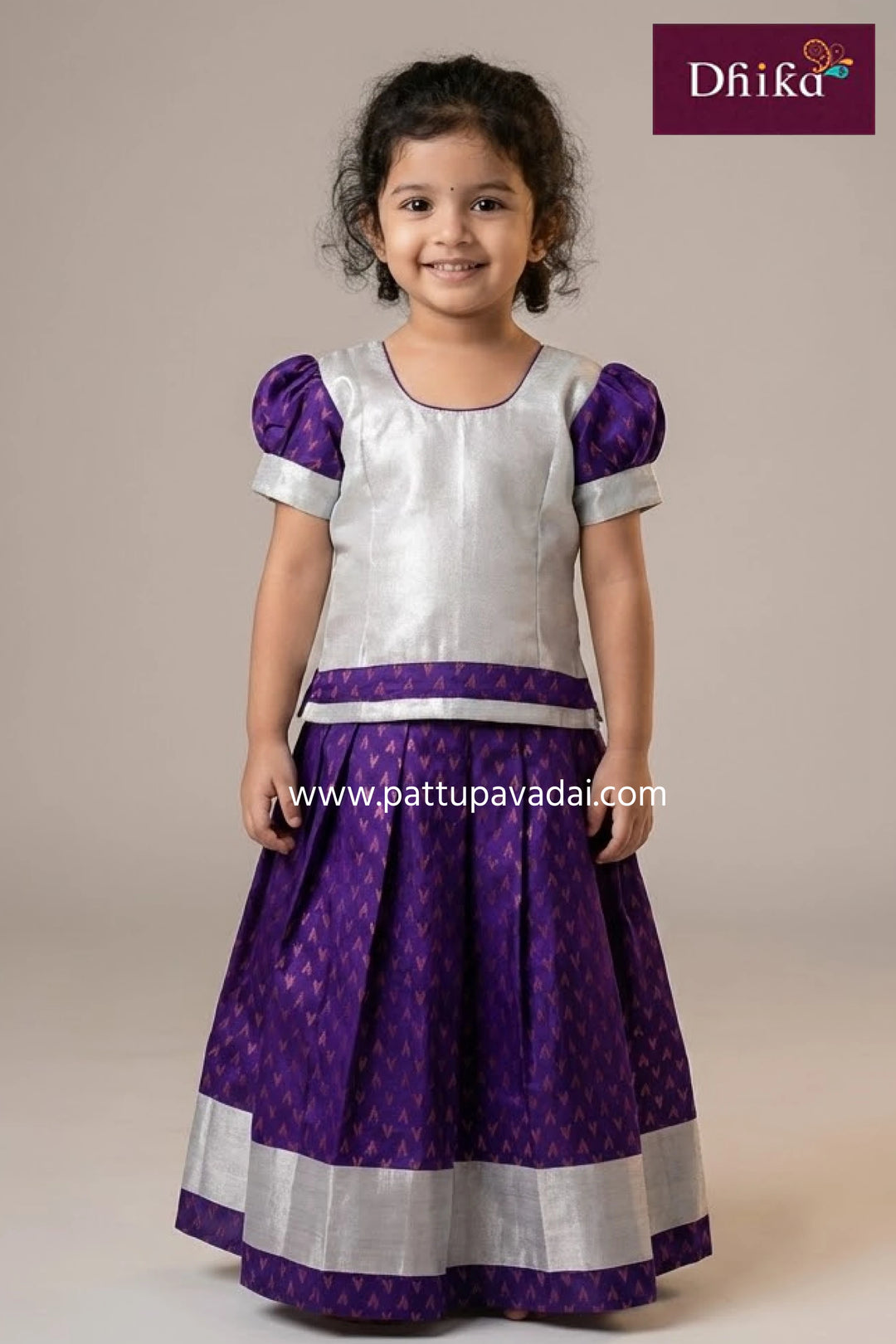 Young girl wearing a purple and white traditional outfit with 'Dhika' branding.