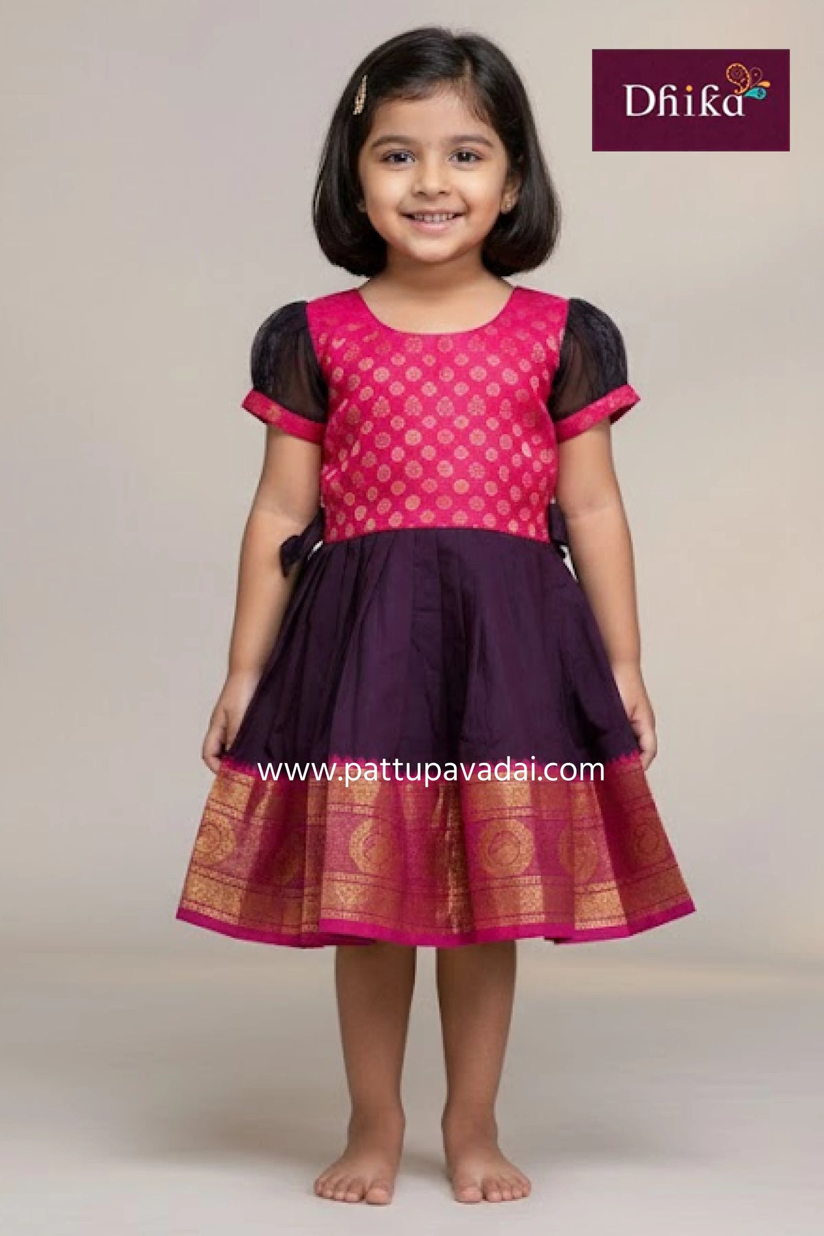 Young girl wearing a pink and purple traditional outfit with 'Dhika' branding.