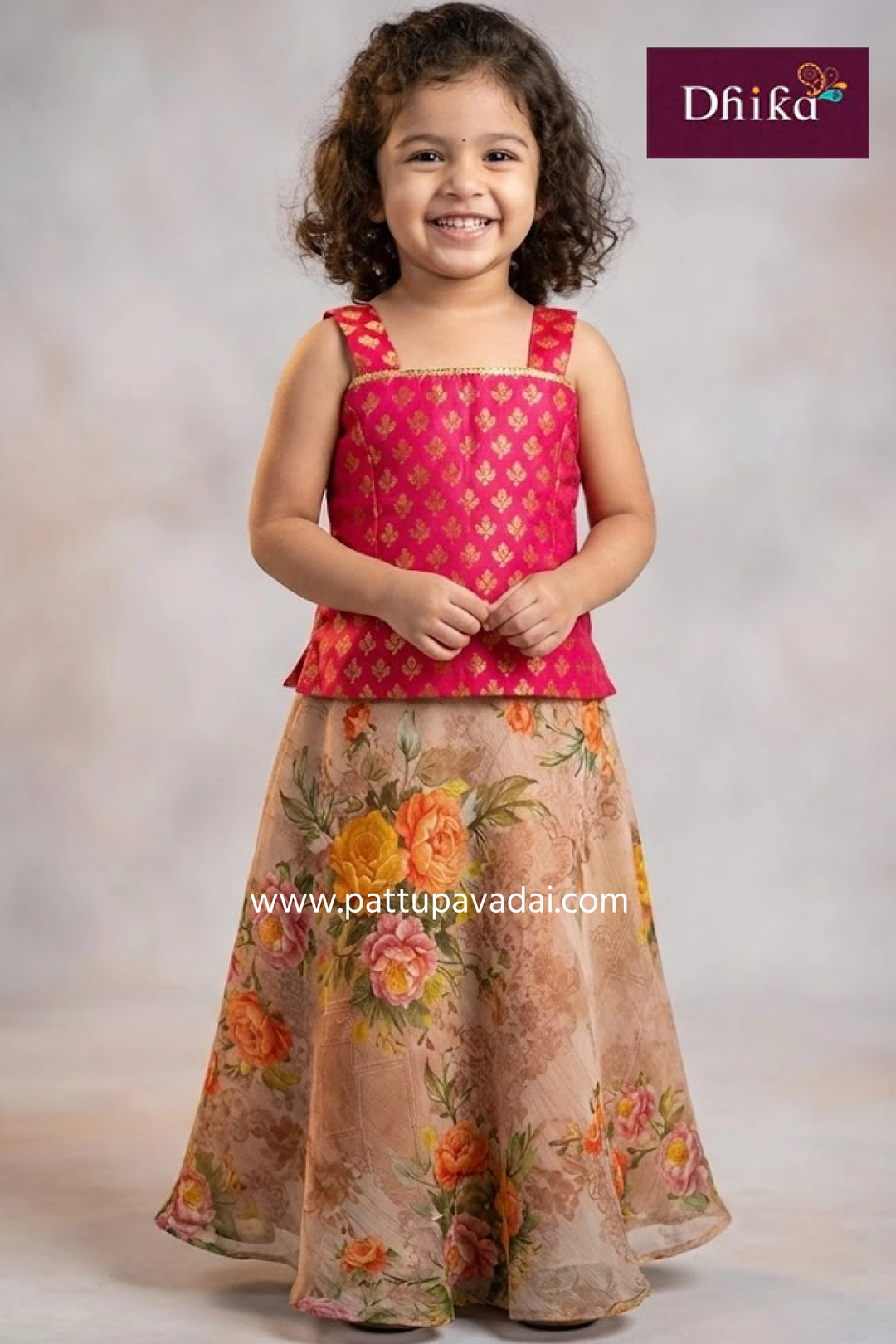 Young girl wearing a pink top and floral skirt with 'Dhika' branding.