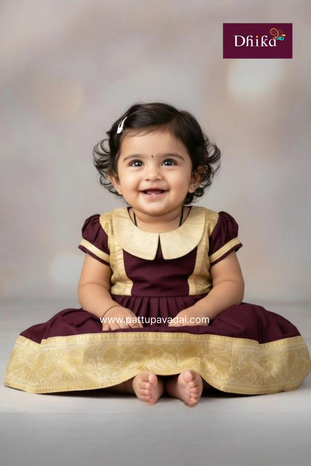 Baby wearing a traditional outfit with a visible brand logo on a plain background