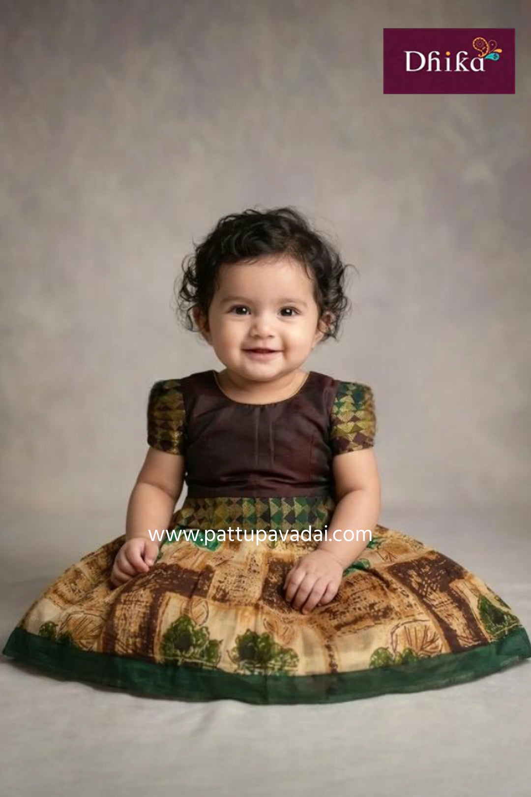 Child wearing a traditional outfit with a brown and green pattern, sitting on a plain background.