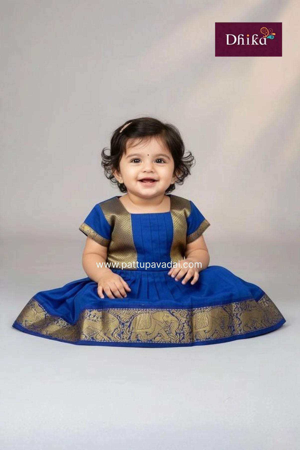 Child wearing a blue traditional outfit with gold details on a white background, featuring the Dhiika brand.