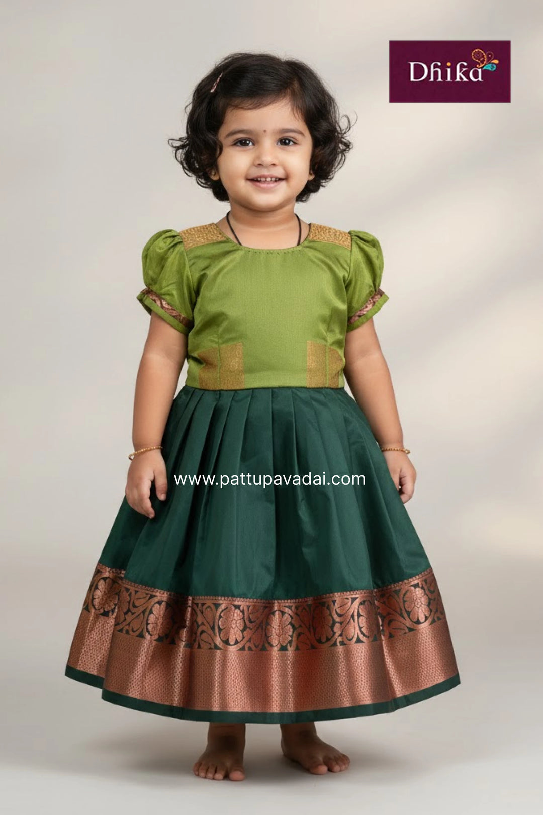 Child wearing a green and brown traditional outfit with 'Dhika' branding.