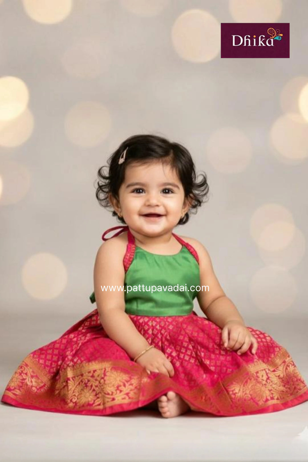 Baby in a green and pink traditional outfit with a blurred light background