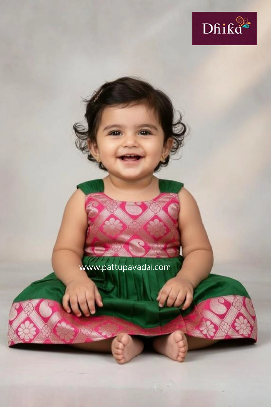 Child wearing a pink and green traditional outfit with 'Dhika' branding.