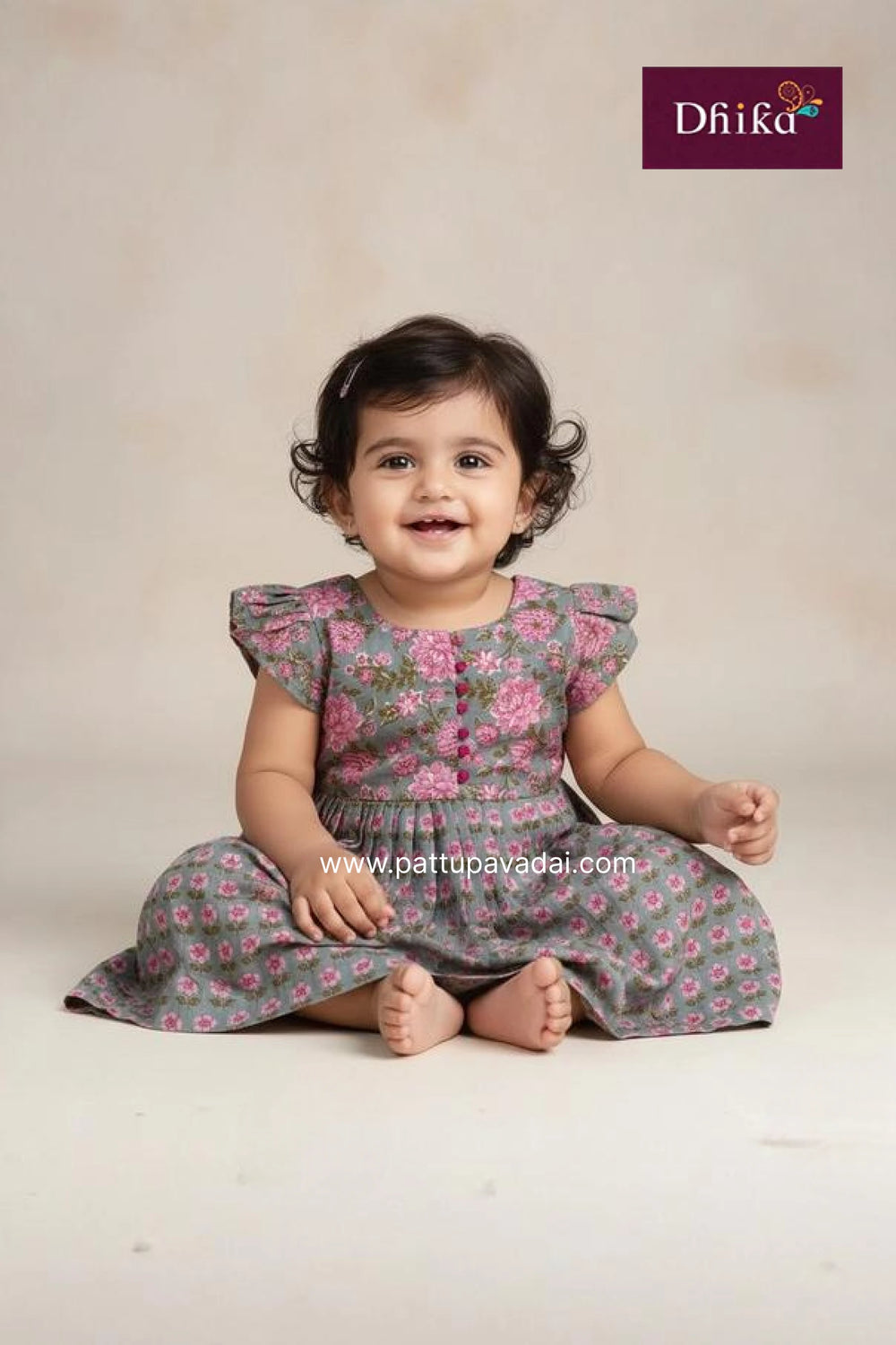 Baby wearing a floral dress sitting on a plain background with Dhika brand logo.