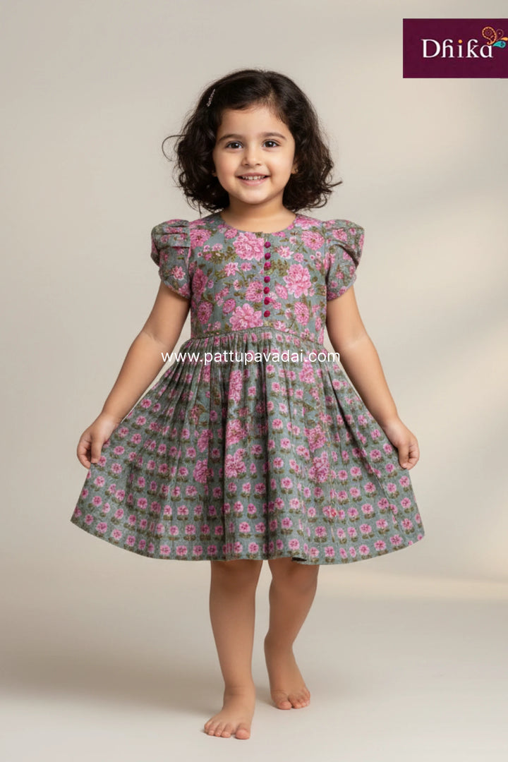 Young girl wearing a floral dress on a plain background with 'Dhika' branding.