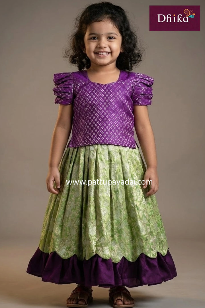 Young girl wearing a purple and green traditional outfit with 'Dhika' branding.