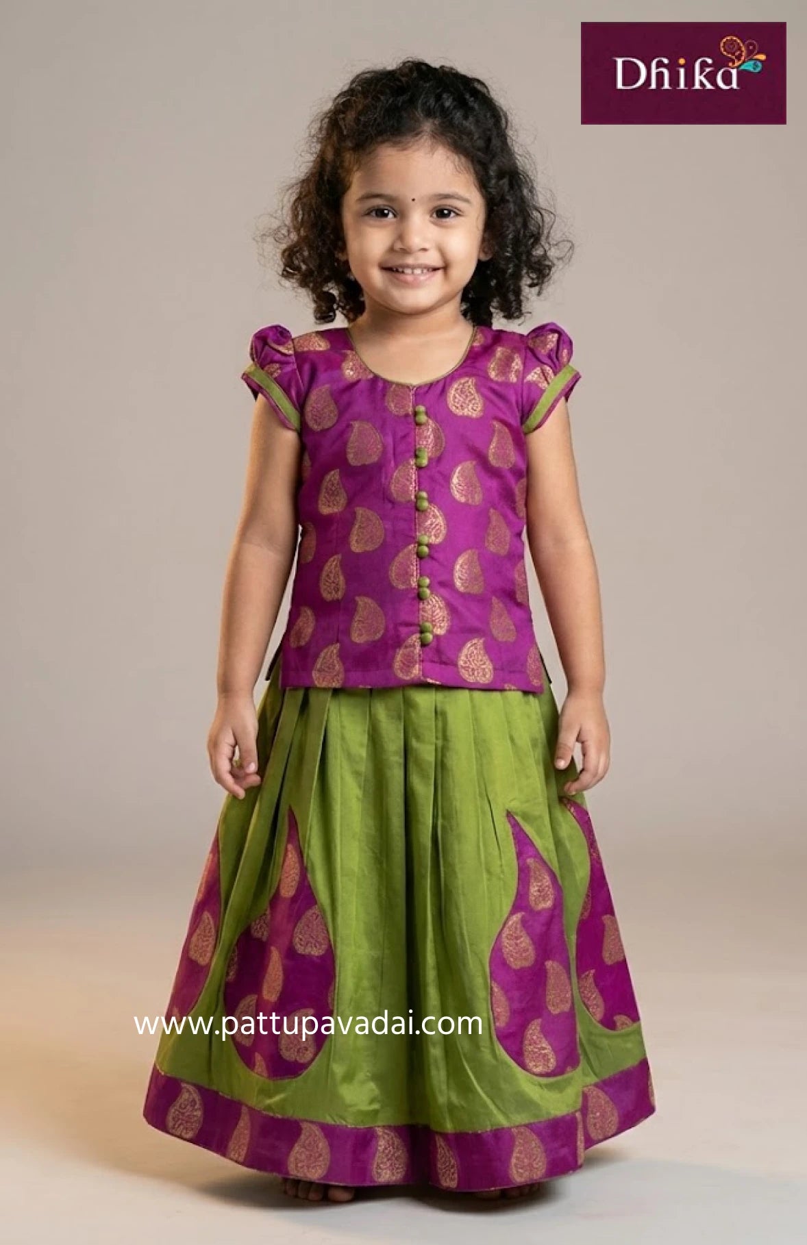 Young girl wearing a purple and green traditional outfit with 'Dhika' branding.