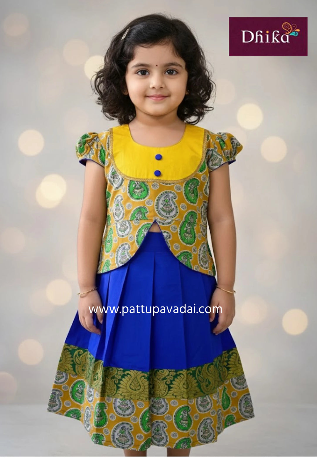 Young girl wearing a colorful traditional outfit with a yellow top and blue skirt, standing against a soft light background.