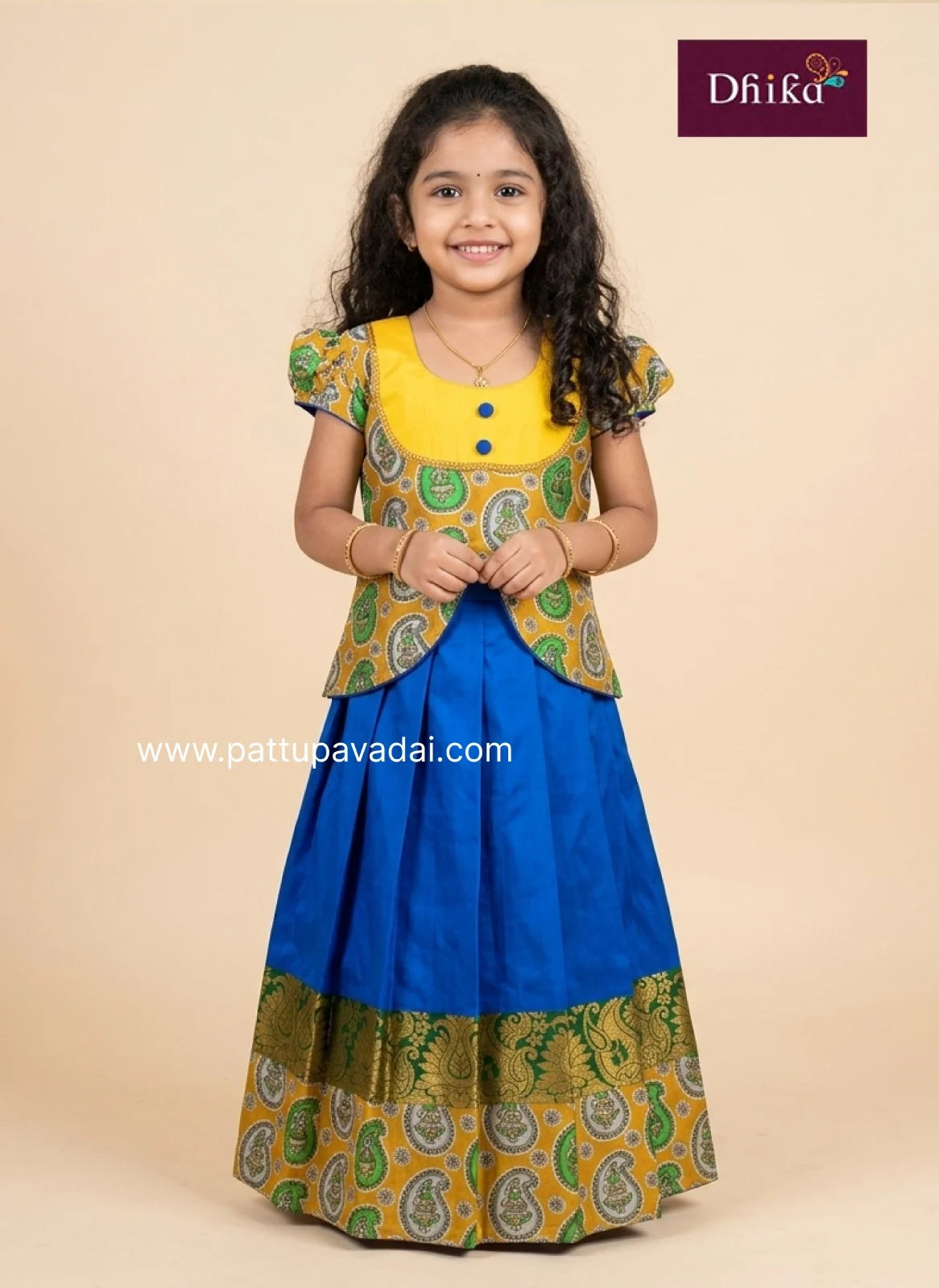 Young girl wearing a traditional outfit with a yellow top and blue skirt, brand 'Dhika' visible.