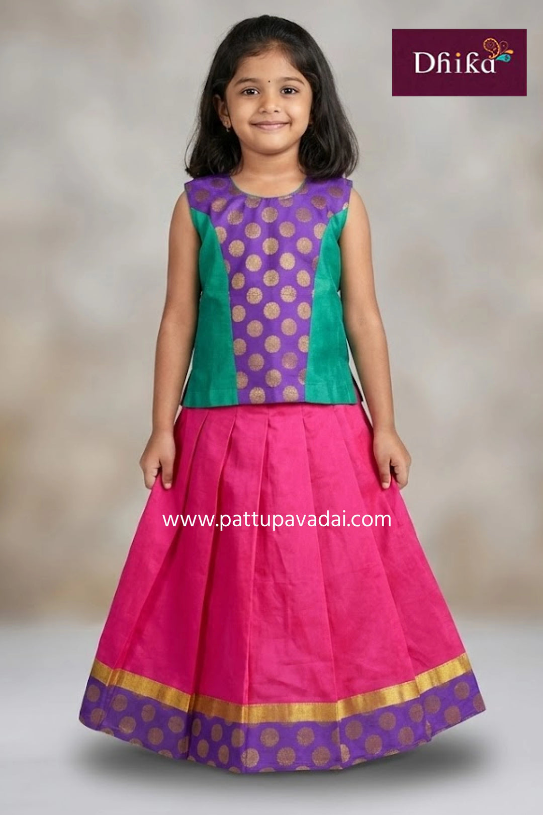 Young girl wearing a colorful traditional outfit with a pink skirt and purple top, branded 'Dhika'.