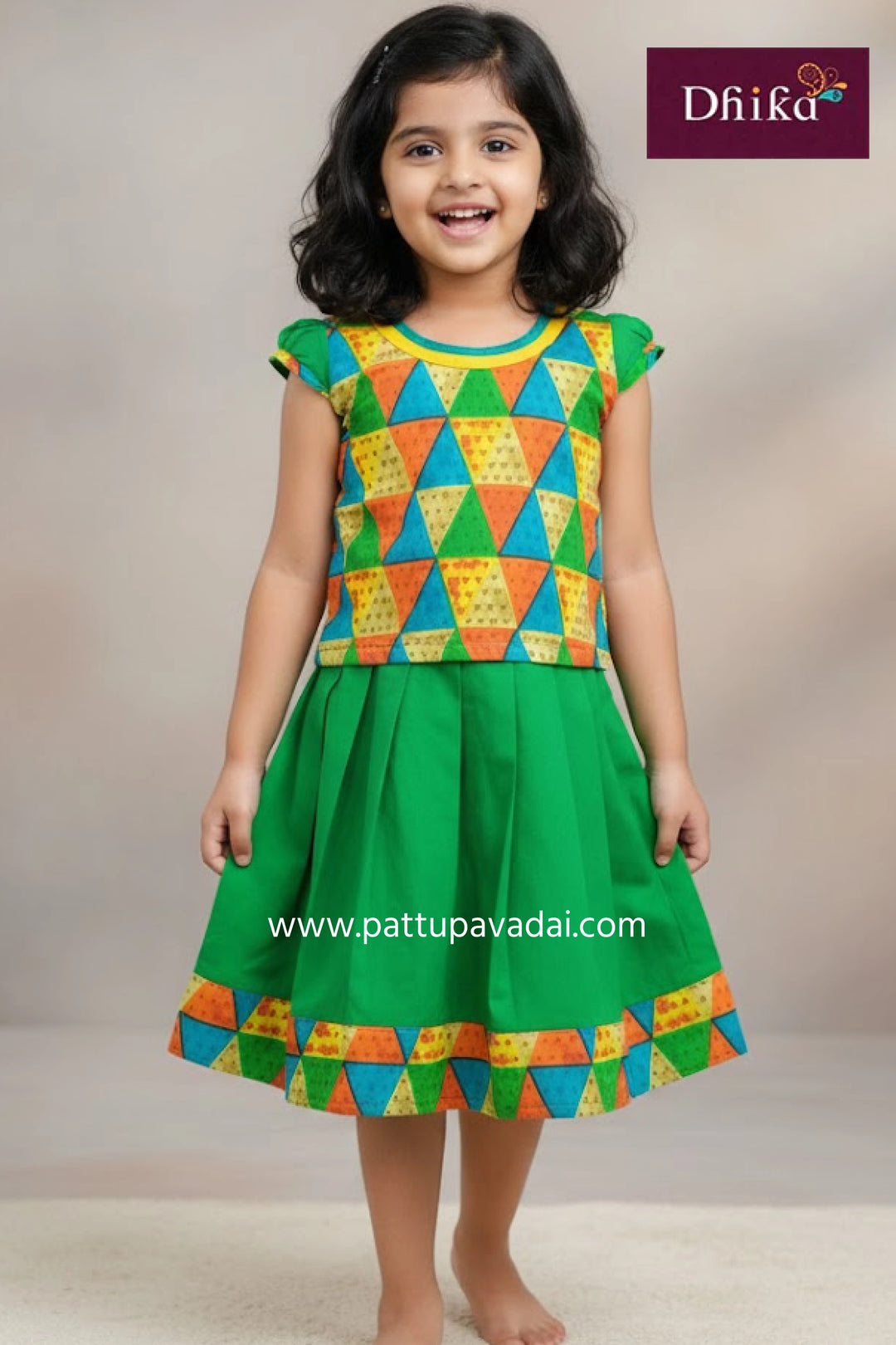 Young girl wearing a colorful geometric-patterned dress with a green skirt, against a neutral background.