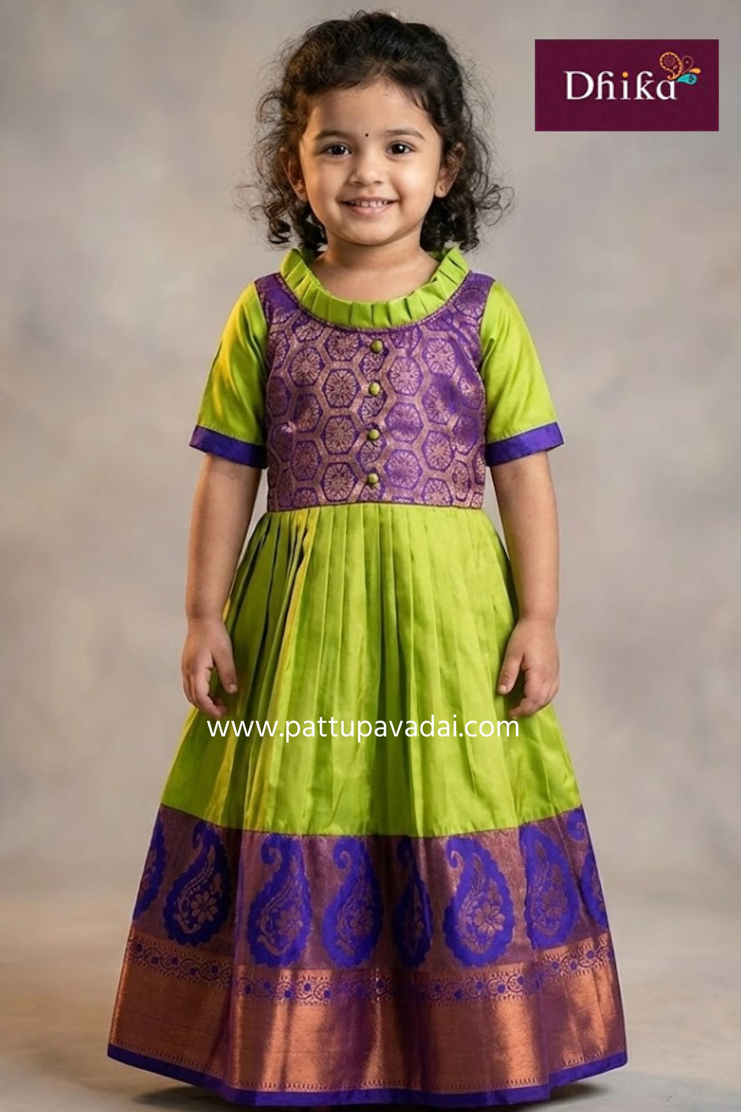Child wearing a green and purple traditional outfit with 'Dhika' branding.