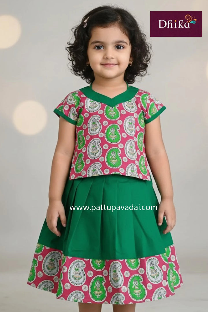 Young girl wearing a pink and green patterned top with a matching skirt, branded 'Dhika'.
