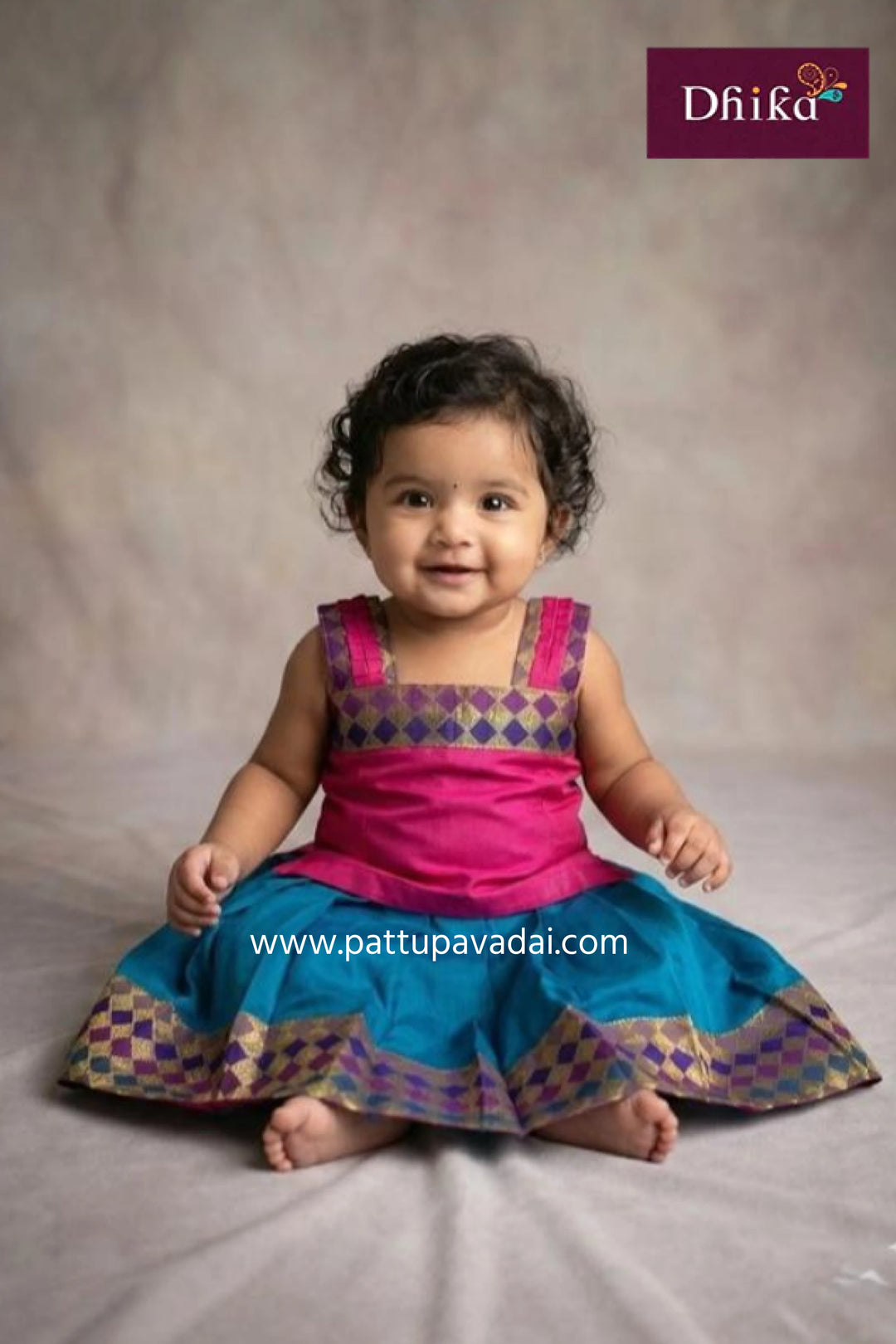 Child wearing a pink and blue traditional outfit with 'Dhika' branding.