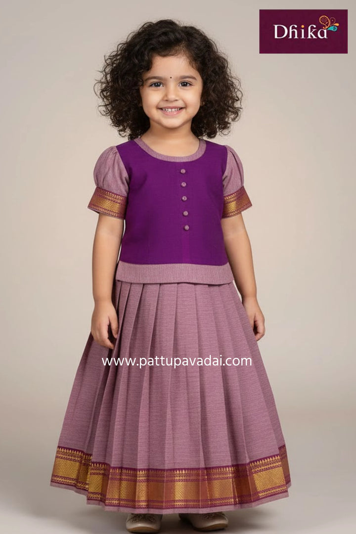 Young girl wearing a purple traditional outfit with gold accents, standing against a plain background.