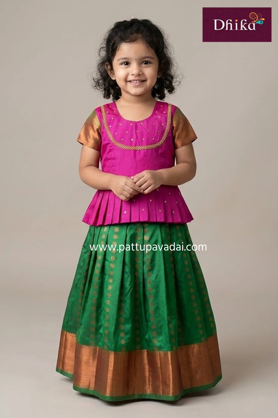 Young girl wearing a traditional outfit with a maroon and gold pattern, standing against a plain background.