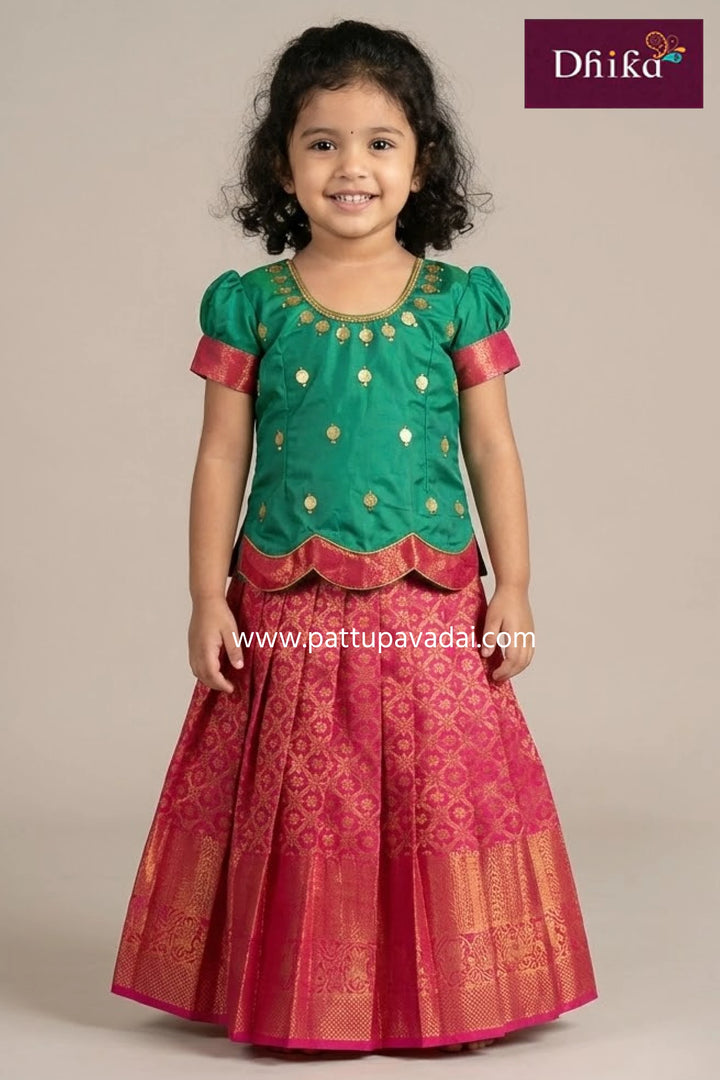 Young girl wearing a green and red traditional outfit with 'Dhika' branding.