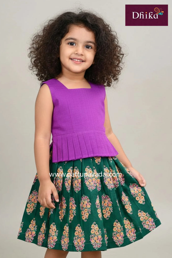 Child wearing a purple top and green floral skirt with 'Dhika' branding.