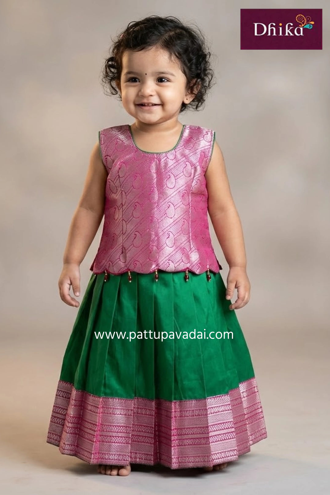 Young girl wearing a traditional blue and pink saree with gold embroidery, standing against a plain background.