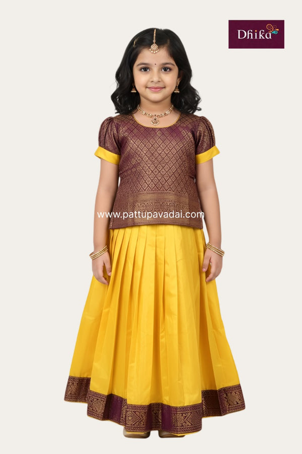 Young girl wearing a yellow and brown traditional outfit with 'Dhika' branding.