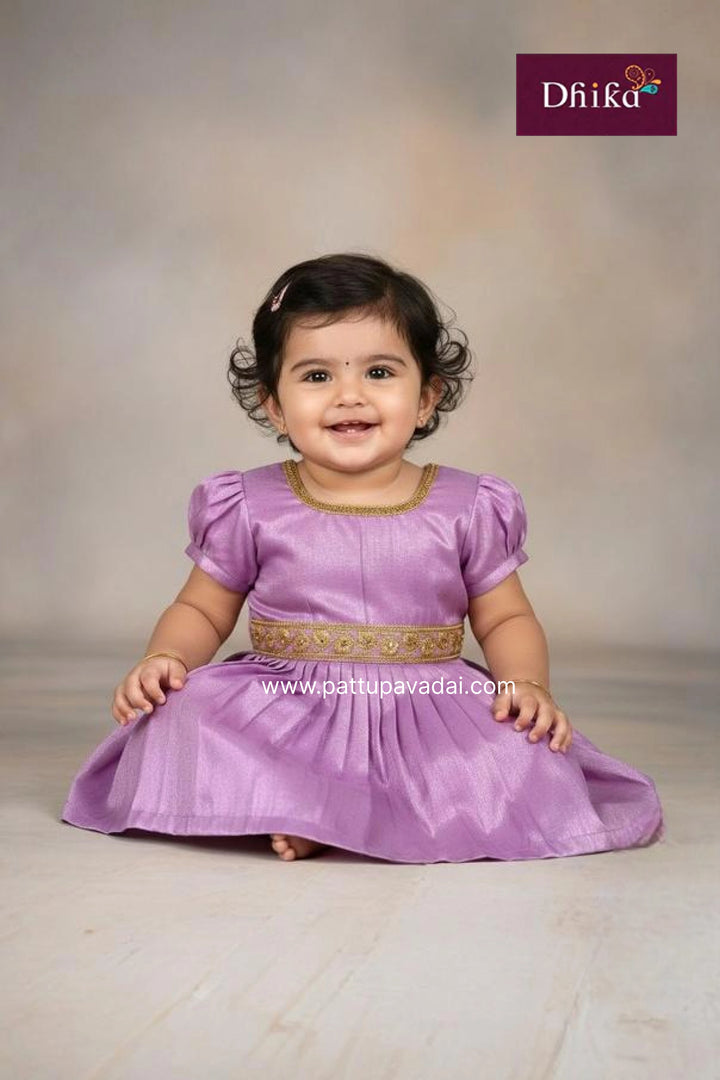 Child wearing a purple dress with gold accents, sitting on a plain background.