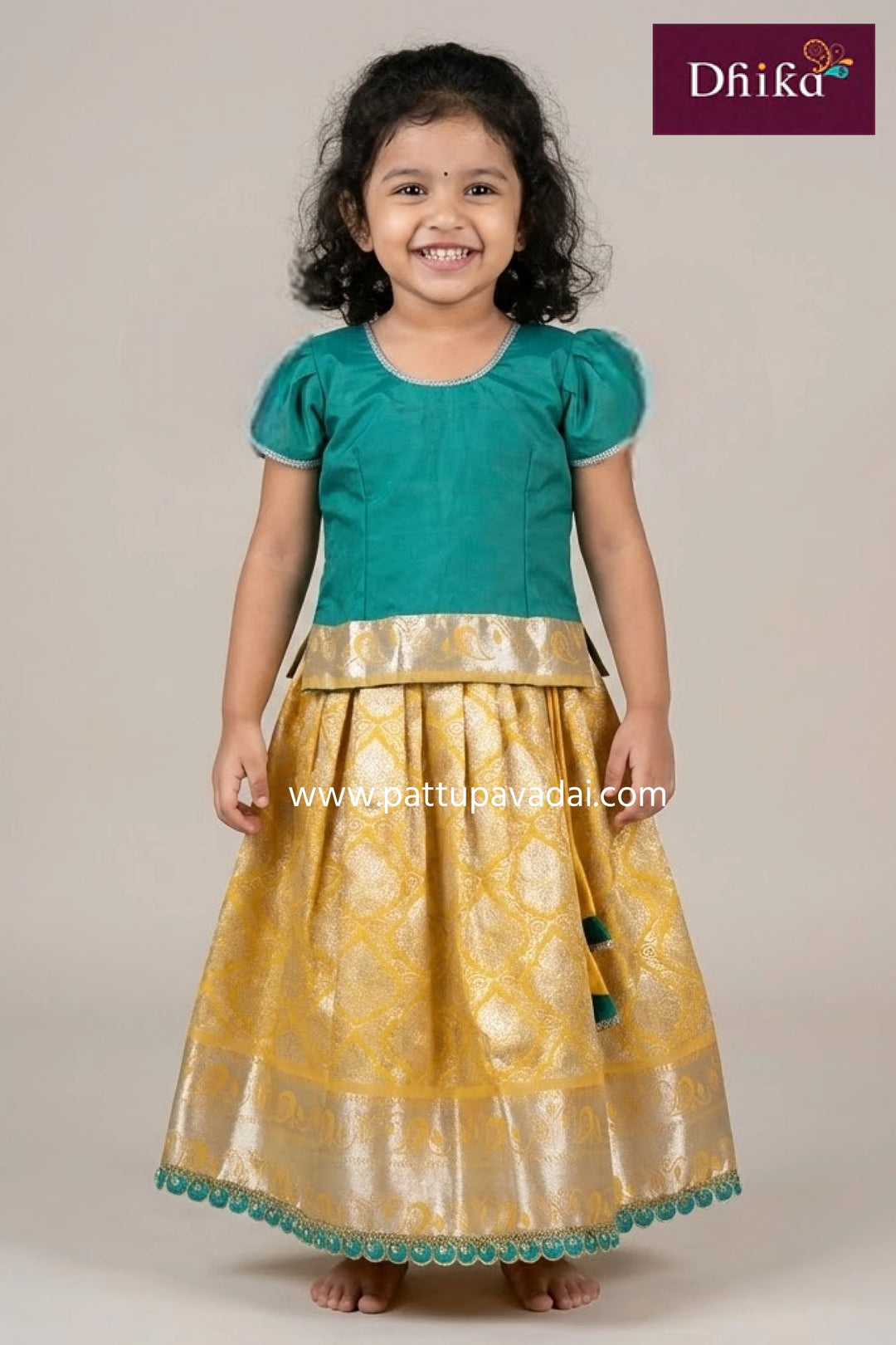 Young girl wearing a green top and yellow skirt with floral patterns, standing against a plain background.