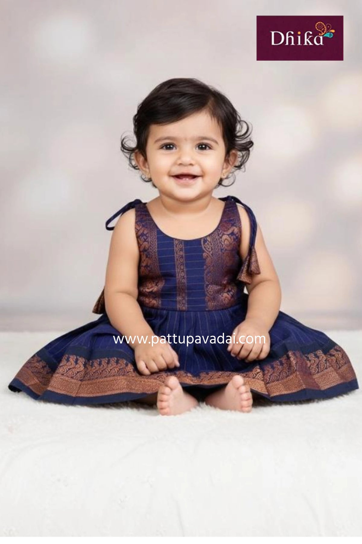 Baby wearing a traditional outfit with a visible brand logo on a light background