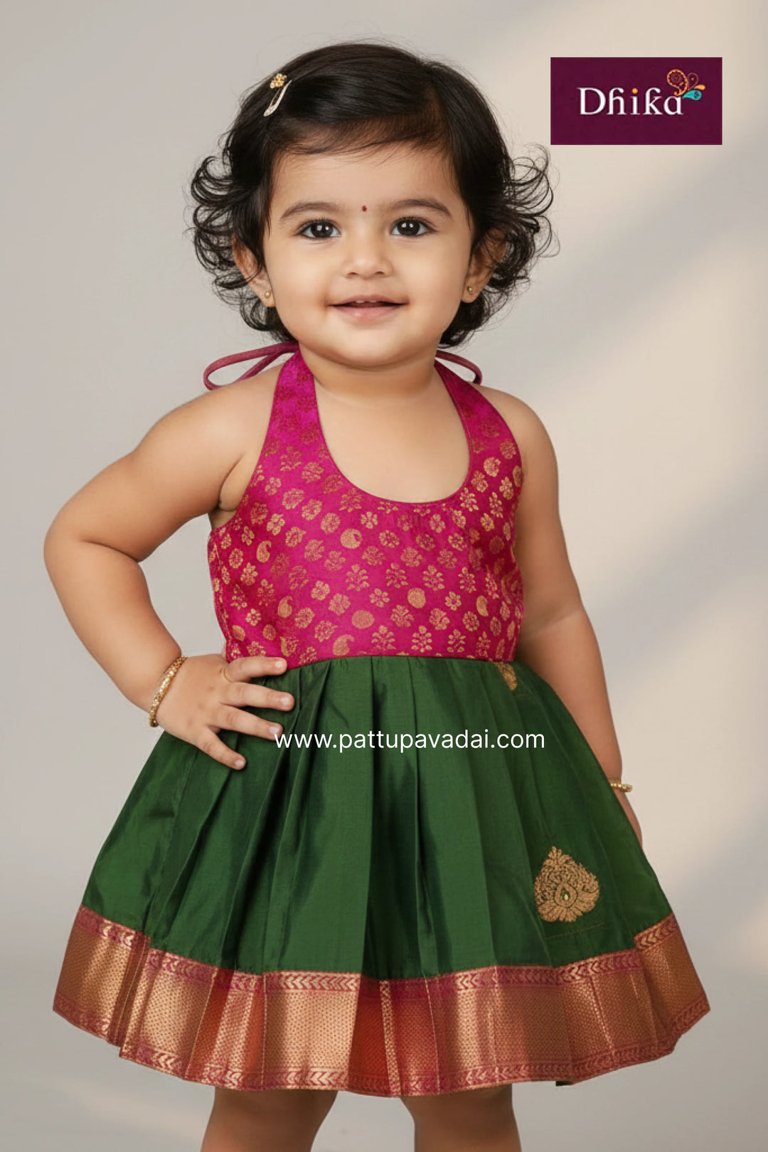 Child wearing a pink and green traditional outfit with 'Dhika' branding.