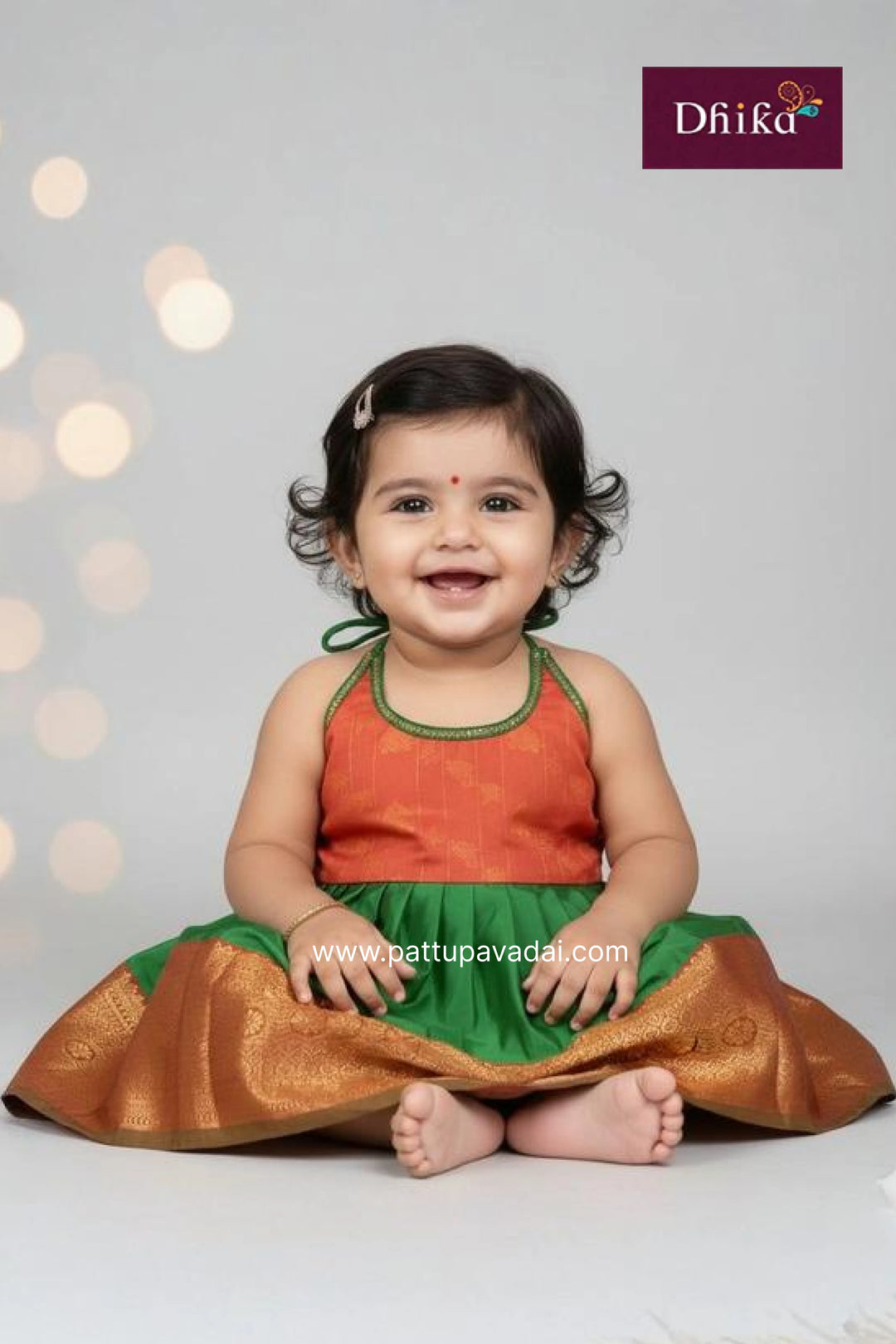 Baby wearing traditional attire with a white background and 'Dhika' branding.