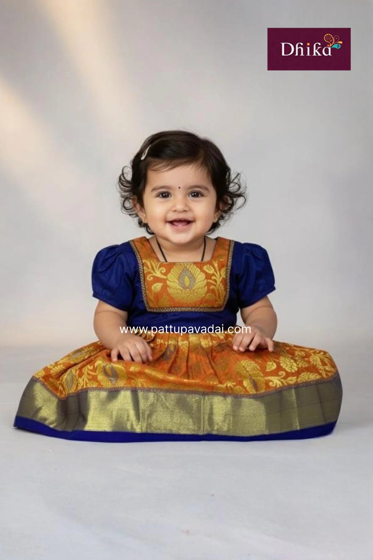 Child wearing a traditional outfit with gold and blue colors on a white background, featuring the Dfiika brand.