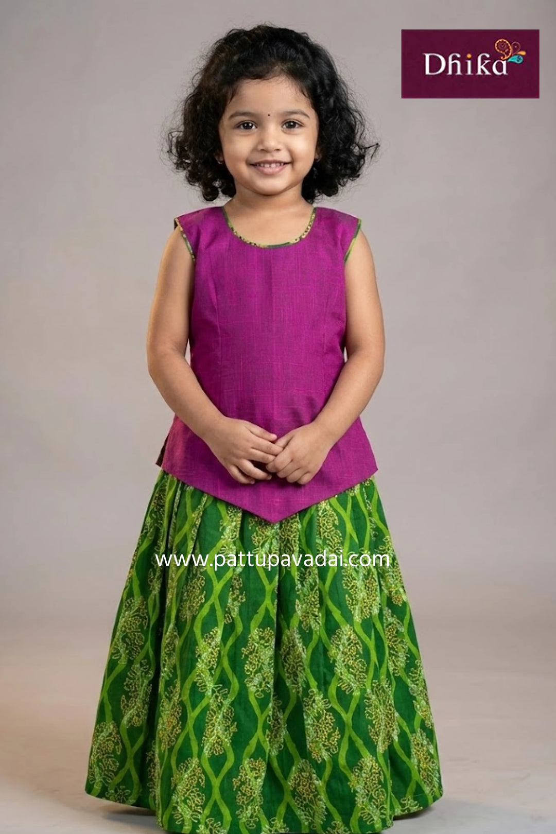 Young girl wearing a purple top and green patterned skirt with 'Dhika' branding.
