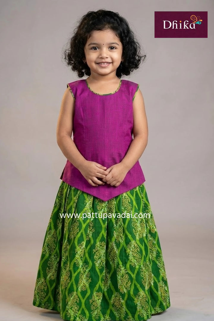 Young girl wearing a purple top and green patterned skirt with 'Dhika' branding.