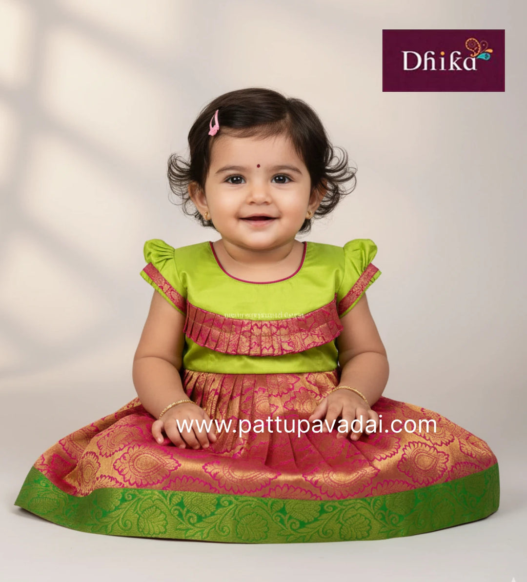 Child wearing a green and pink traditional outfit with 'Dhika' branding.