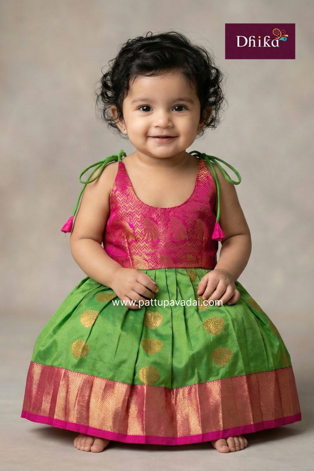 Child wearing a green and pink traditional outfit with Dhiika branding.