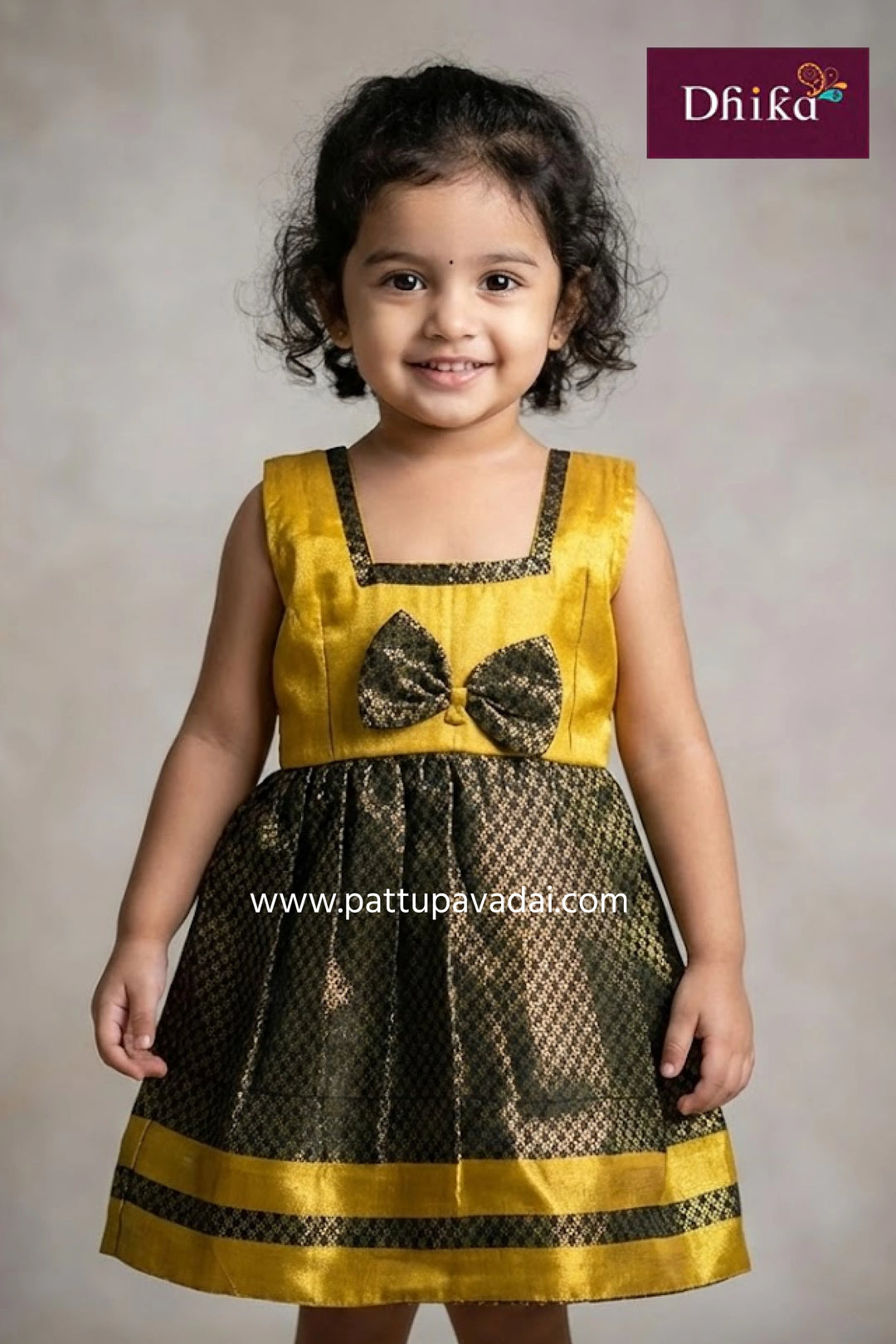 Child wearing a yellow and black dress with a bow detail, branded 'Dhika'.