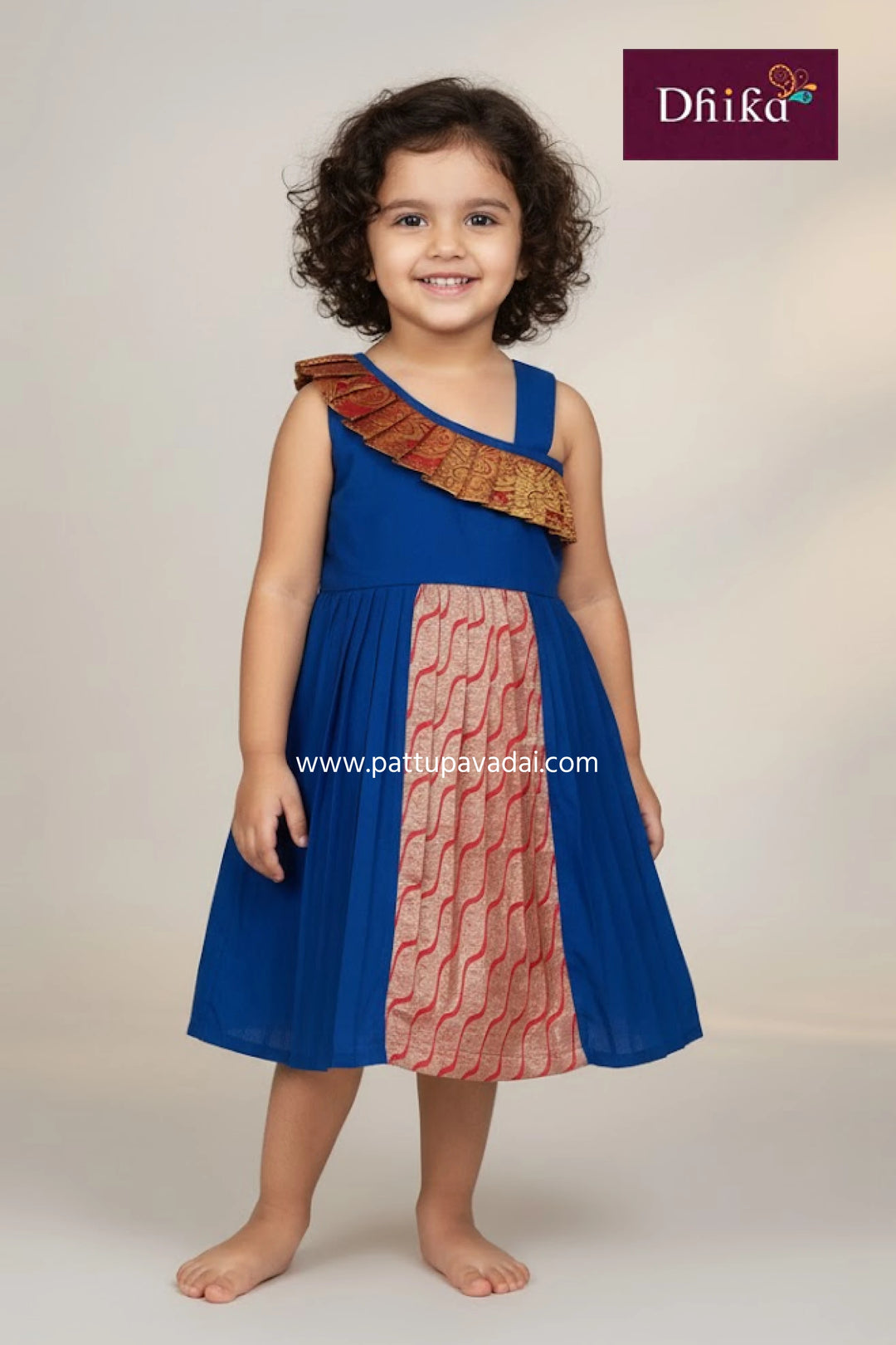 Child wearing a blue and red dress with a textured pattern, standing against a plain background.
